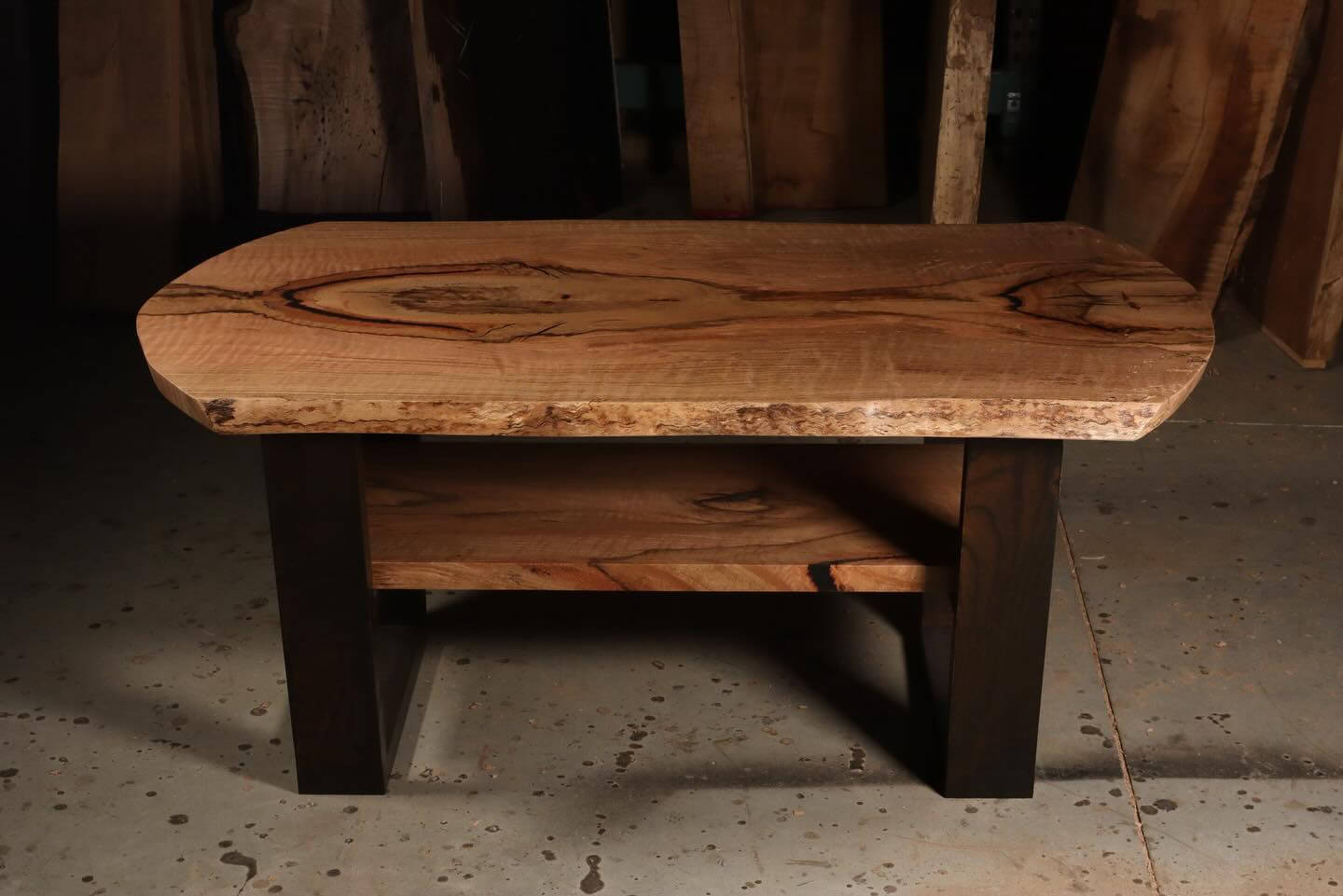 Rustic wooden coffee table with natural wood grain, featuring a sturdy design and dark legs, set in a workshop environment.