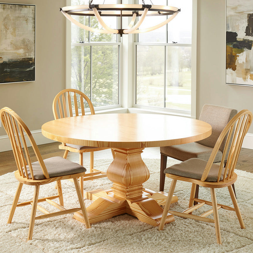 Dining room with wooden table and chairs in front of large windows.