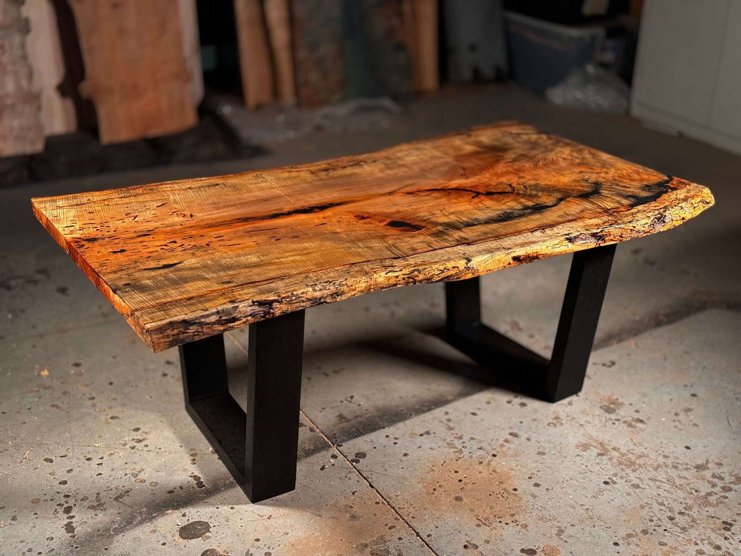 Live edge wood coffee table with natural wood tones and sleek black metal legs, showcasing unique grain and rustic charm.