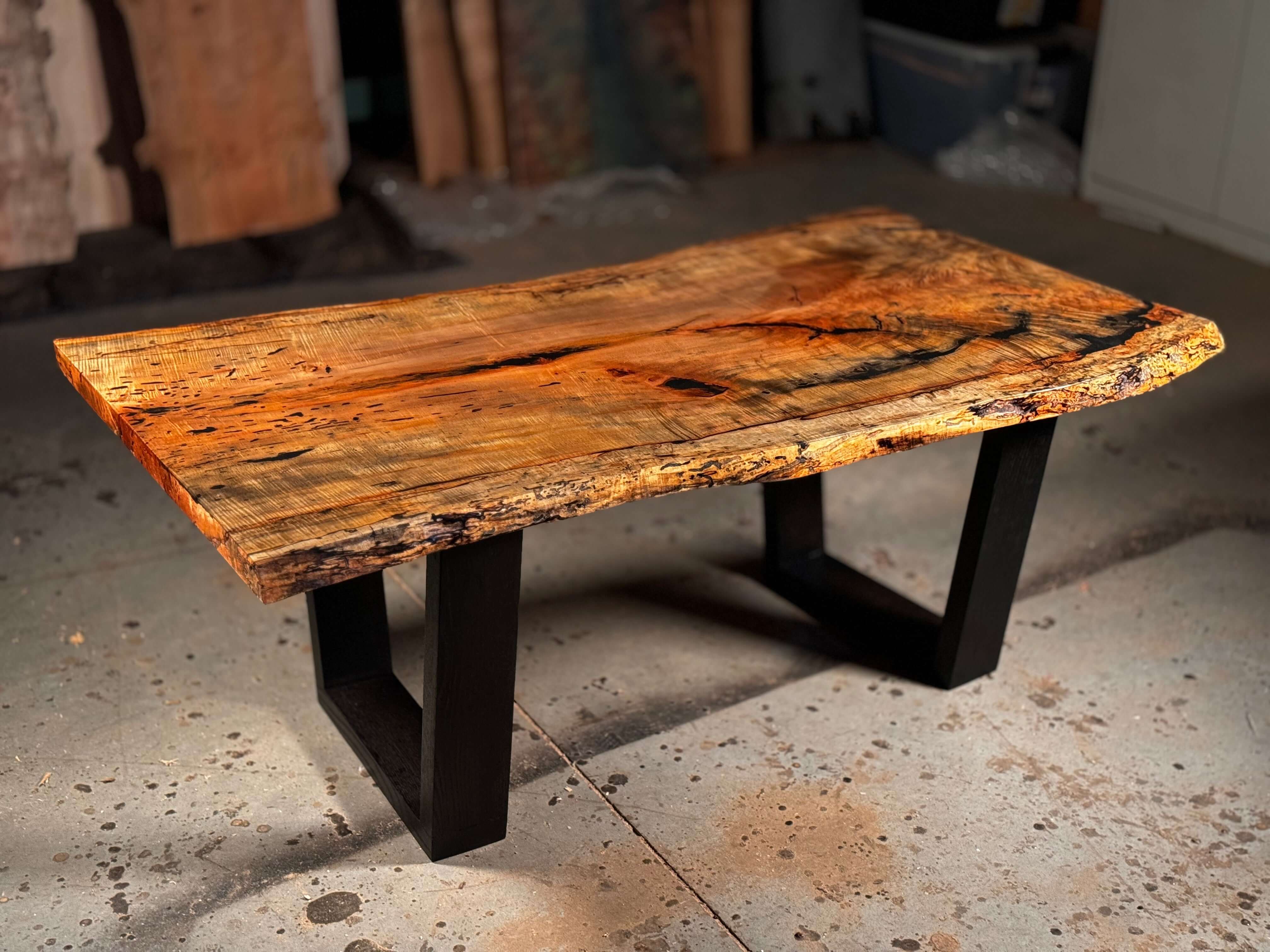 Live edge wood coffee table with natural wood tones and sleek black metal legs, showcasing unique grain and rustic charm.
