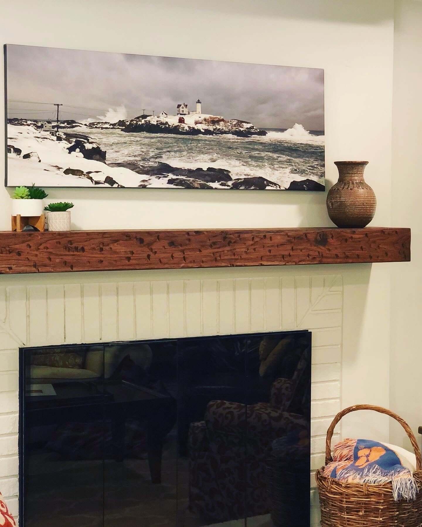 Rustic solid wood hand-hewn mantel with dark walnut stain in cozy living room setting with decor.