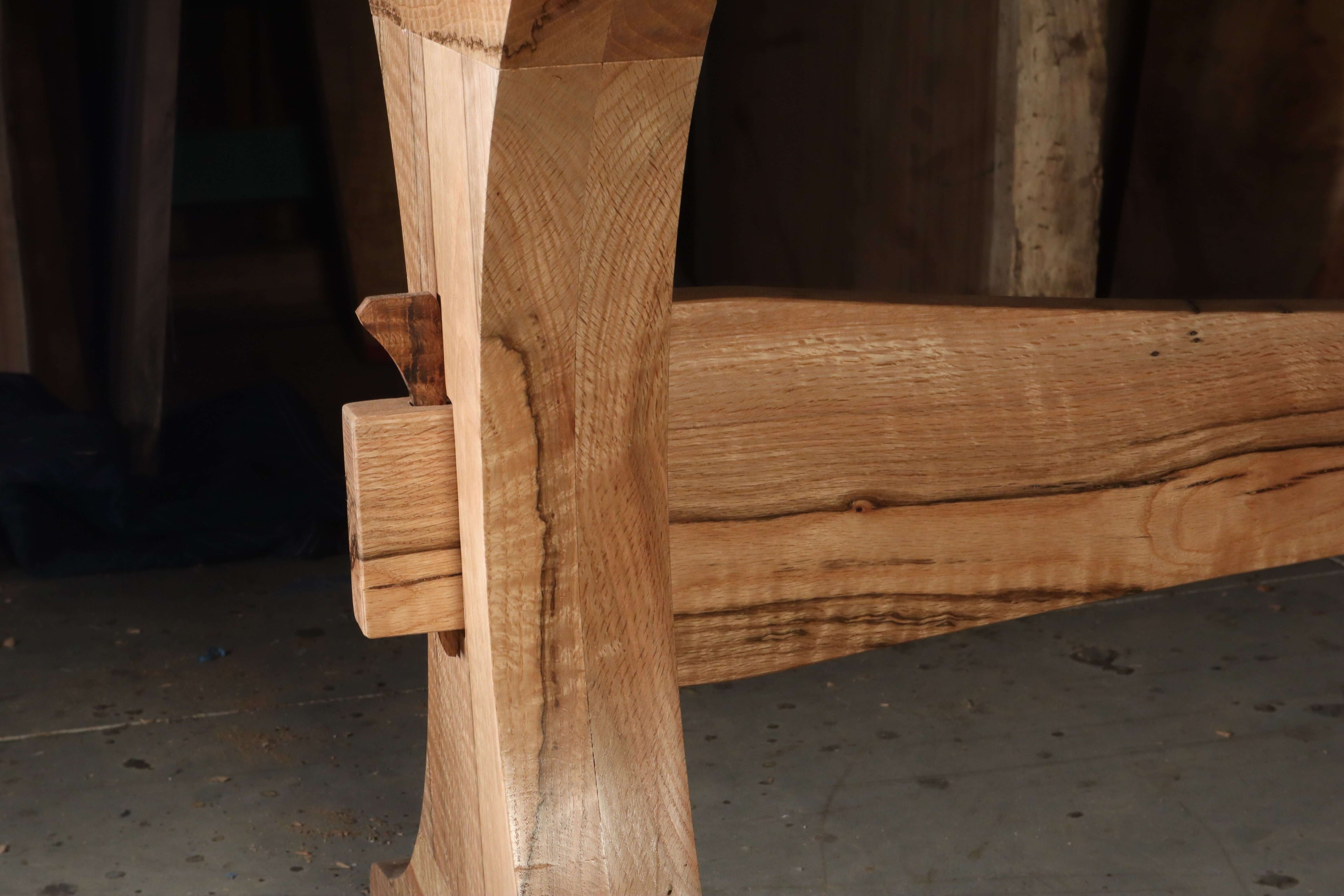 Close-up of solid wood joinery on The Finn Trestle Dining Table base, showcasing its elegant curved design and craftsmanship.