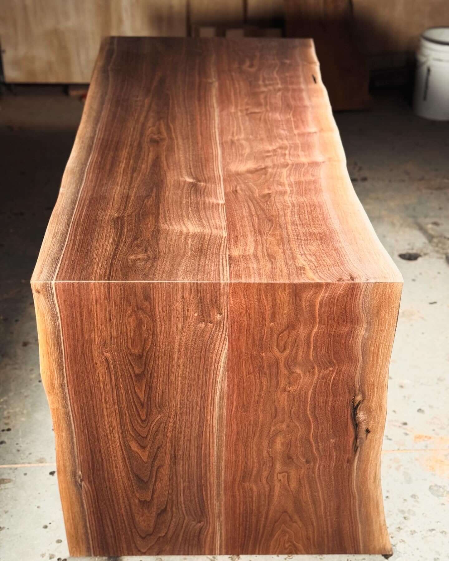 Live edge waterfall desk with seamless design and unique lines in natural wood finish. Perfect for modern and rustic spaces.