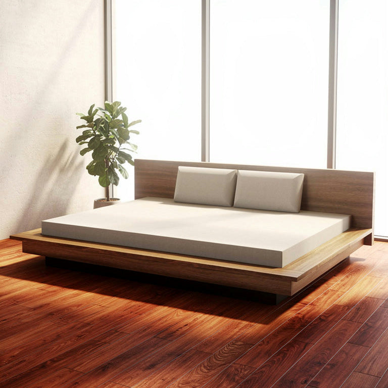 Wooden platform bed with white mattress and pillows in a room with large windows.