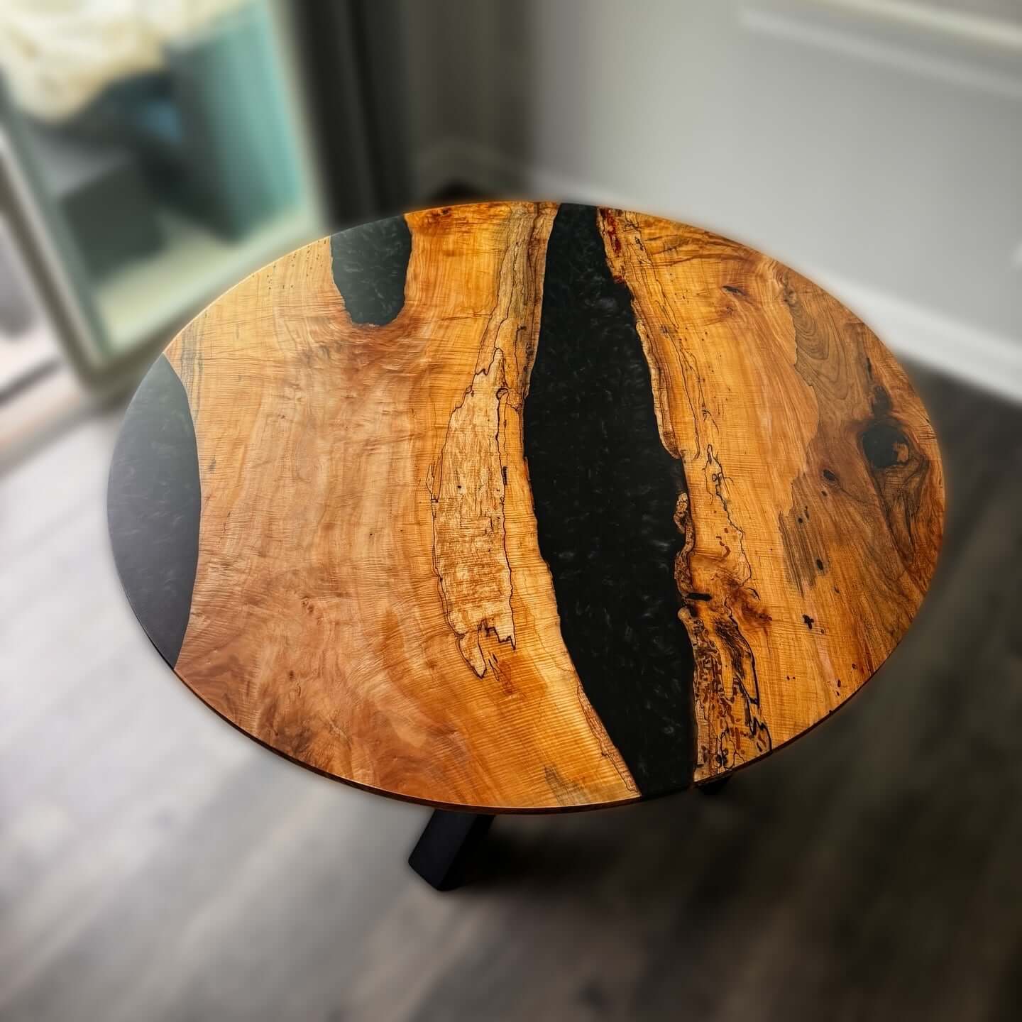 Modern round epoxy river table with a striking wood and black epoxy design, ideal for enhancing any room's style and elegance.