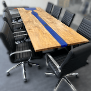 Large epoxy river conference table with blue epoxy and natural wood finish, surrounded by black office chairs in a meeting room.