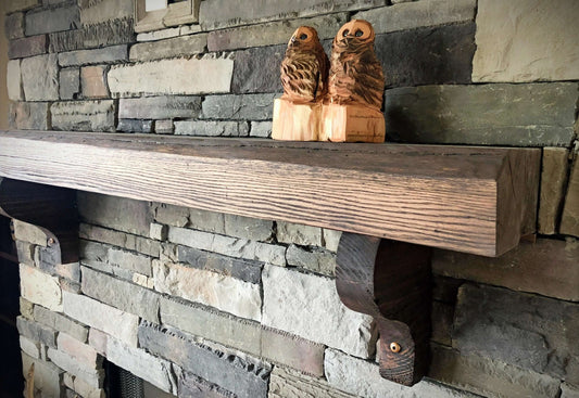 Red Oak Mantle with Provincial Stain against a stone wall, featuring carved wooden owl decorations.