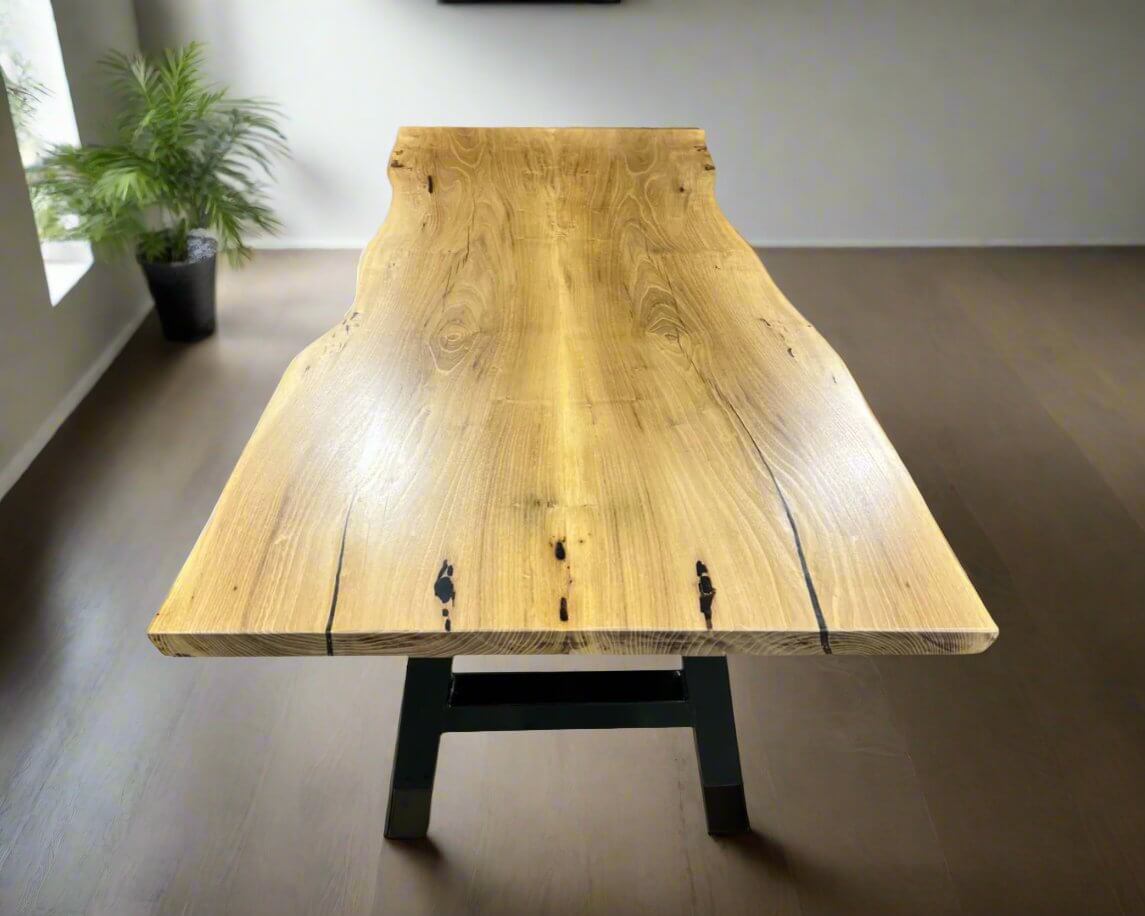 Book-matched live edge table with a natural wood finish and metal legs displayed in modern room setting.