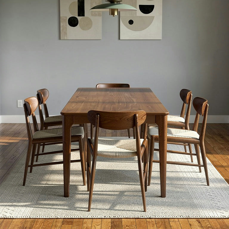 Dining room with wooden table and chairs against a gray wall with abstract art.