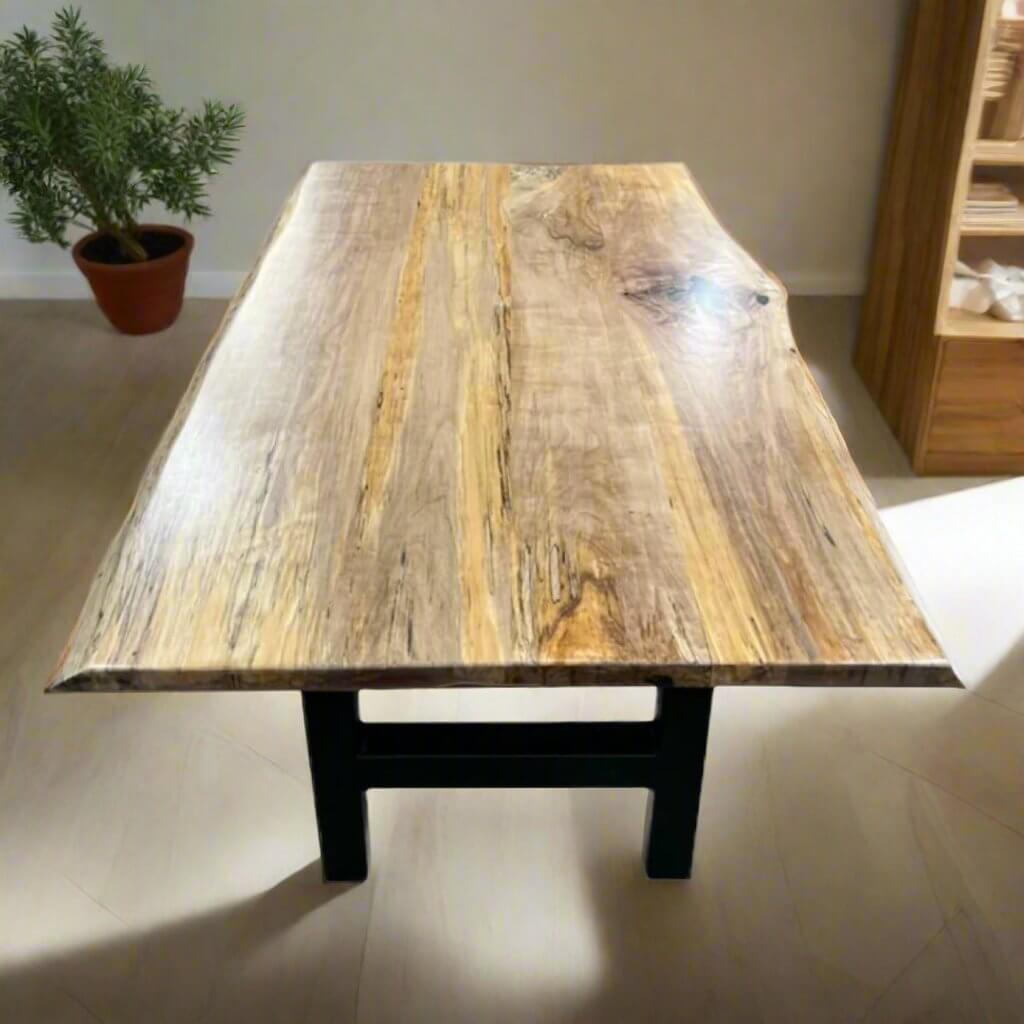 Book-matched live edge table with natural wood grain and metal legs in a modern room setting.