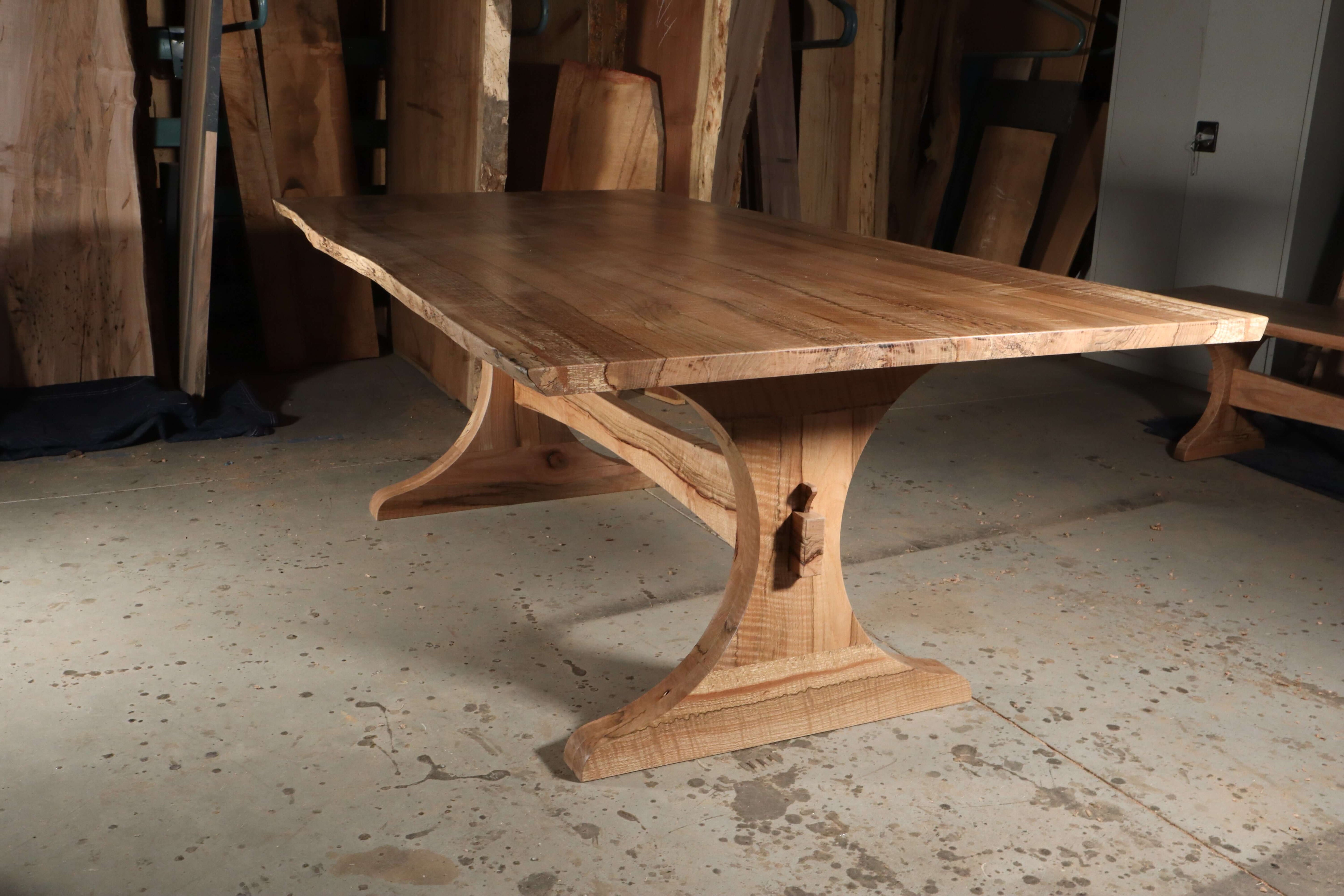 Elegant solid wood trestle dining table with curved base design, showcasing The Finn for modern or traditional style dining rooms.
