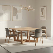 Modern dining room with wooden table and gray chairs, light-colored walls, and abstract art.