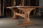 Rustic solid wood trestle dining table with unique curved design, customizable in size and wood species for a lasting family statement piece.