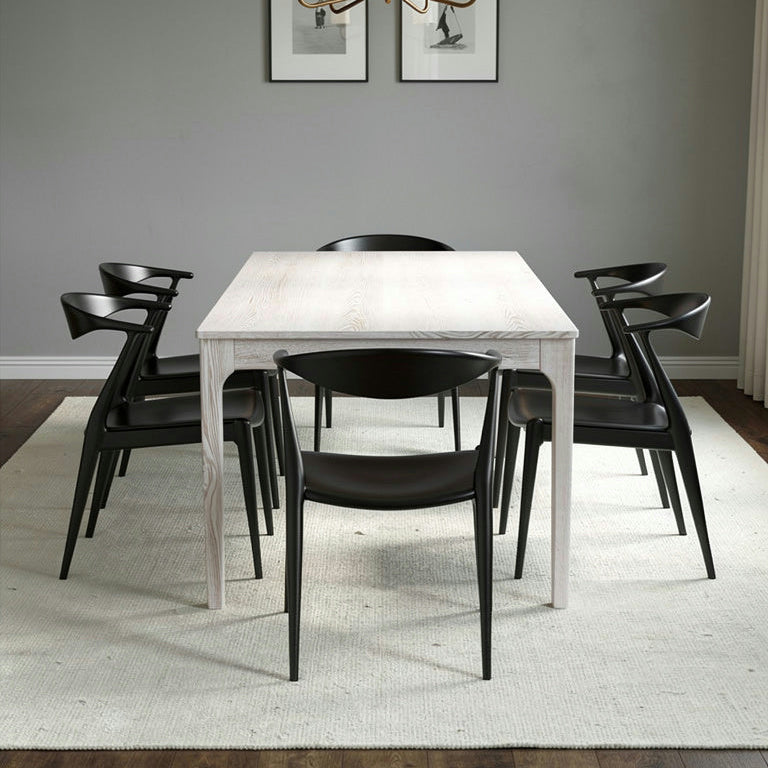 Dining room with a white table and black chairs, gray walls, and a chandelier.